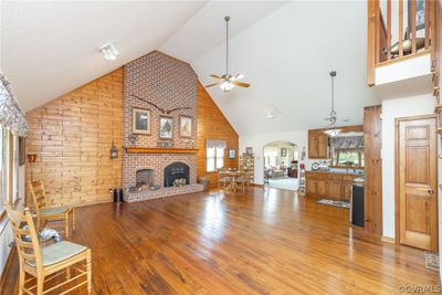 Living room with a fireplace, ceiling fan, high vaulted ceiling, hardwood / wood-style floors, and wood walls | Image 3