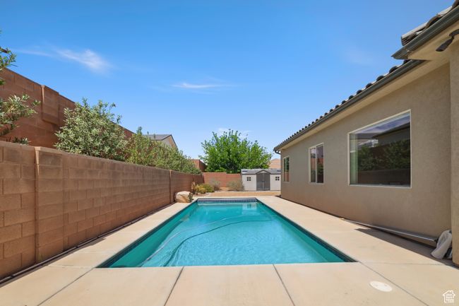 View of pool featuring a fenced in pool, a fenced backyard, an outdoor structure, a patio, and a storage unit | Image 30