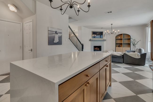 Kitchen featuring a chandelier, a tile fireplace, open floor plan, light stone counters, and a kitchen island | Image 16