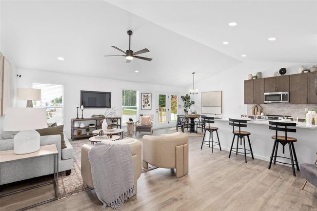 Living room featuring light hardwood / wood-style floors, ceiling fan with notable chandelier, lofted ceiling, and sink | Image 26