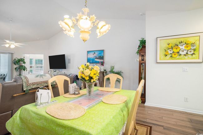 Dining area featuring wood finished floors, lofted ceiling, a chandelier, and ceiling fan | Image 11