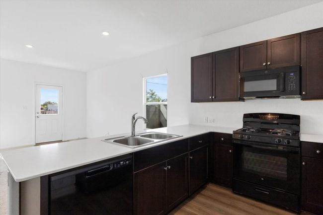 Kitchen with black appliances, a peninsula, healthy amount of natural light, light countertops, and recessed lighting | Image 6