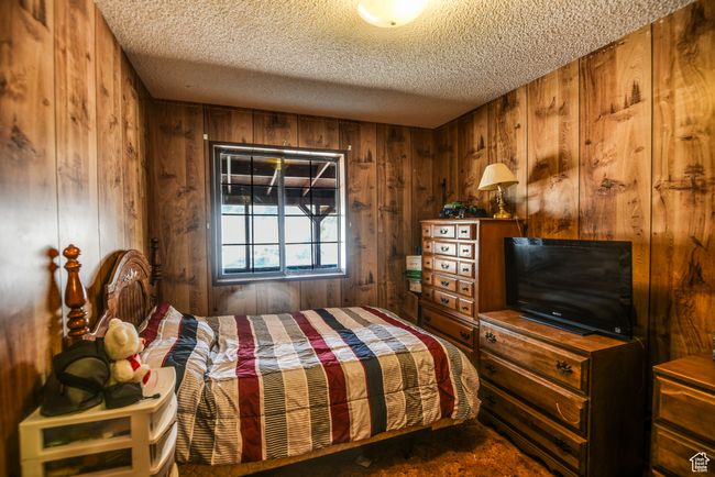 Bedroom featuring wood walls and a textured ceiling | Image 39