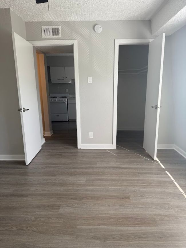 Unfurnished bedroom with a closet, wood finished floors, baseboards, and a spacious closet | Image 16