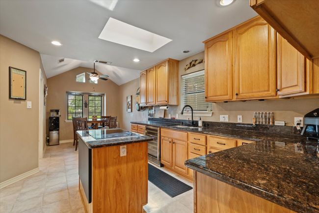 Kitchen with wine cooler, a kitchen island, a skylight, a sink, and ceiling fan | Image 18