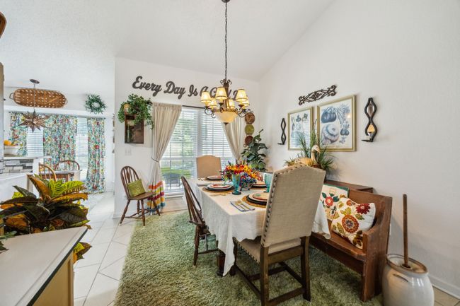 Dining room with a chandelier, lofted ceiling, light tile patterned floors, and baseboards | Image 10