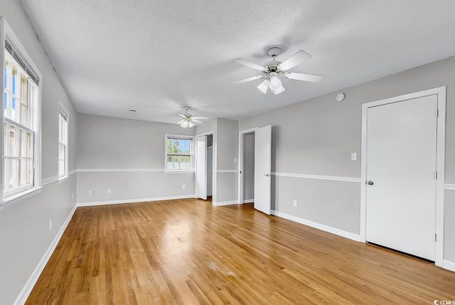Empty room with ceiling fan, light wood finished floors, and a textured ceiling | Image 19