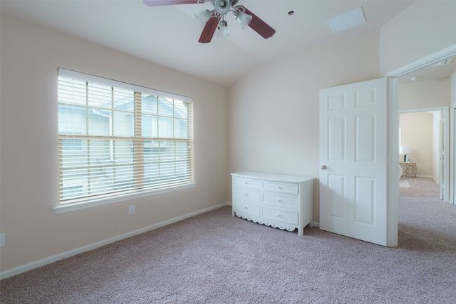 Unfurnished bedroom with baseboards, lofted ceiling, light colored carpet, and ceiling fan | Image 10