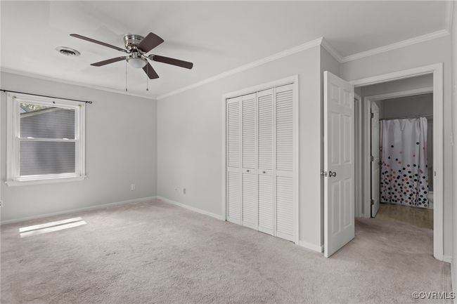 Unfurnished bedroom featuring a closet, visible vents, crown molding, and light colored carpet | Image 30