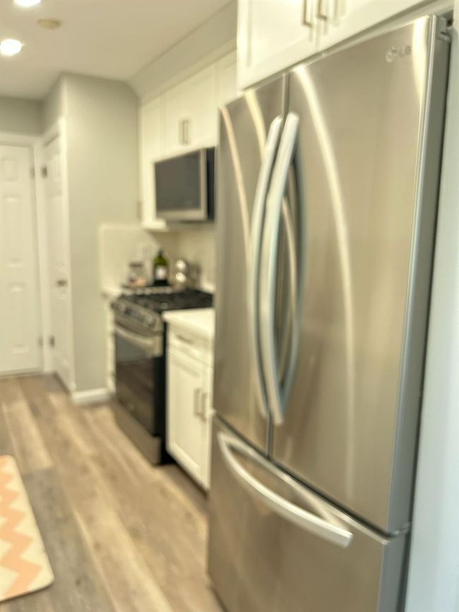 Kitchen featuring stainless steel appliances, white cabinets, and light wood finished floors | Image 11