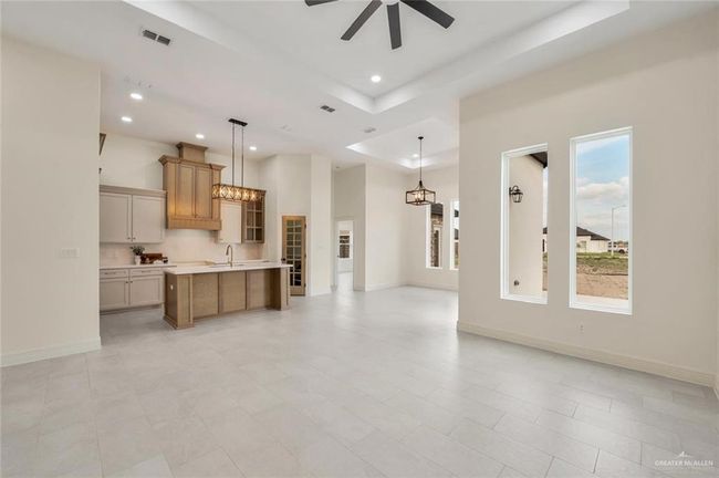 Unfurnished living room featuring a ceiling fan, recessed lighting, a raised ceiling, baseboards, and a towering ceiling | Image 5