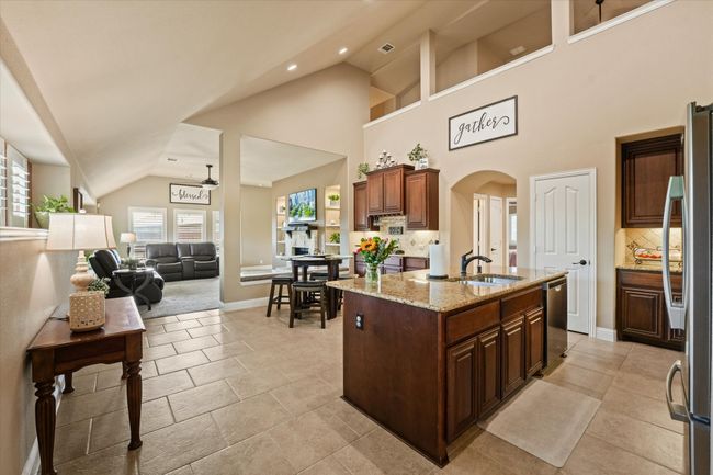 Kitchen with light stone counters, a sink, arched walkways, tasteful backsplash, and appliances with stainless steel finishes | Image 10