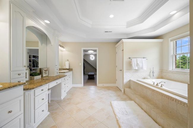 Luxury extends in the master bathroom featuring dual sinks, vanity, large jetted tub, separate commode room and large tiled shower. | Image 26