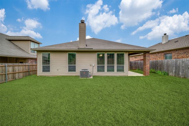 Rear view of house with a fenced backyard, a patio area, and a chimney | Image 17