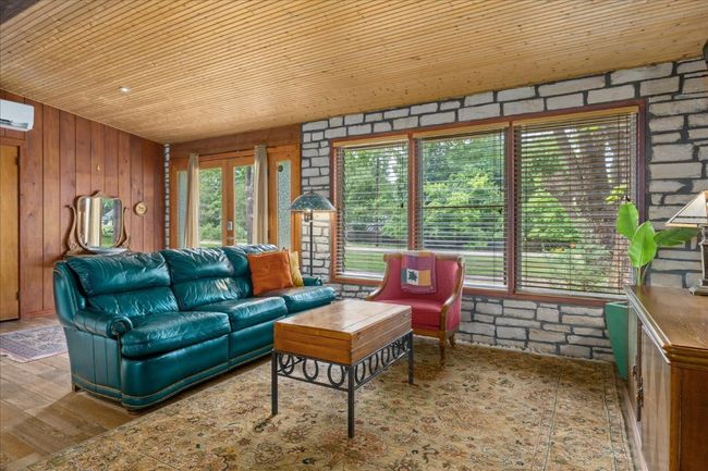 Living area with wood ceiling, wooden walls, healthy amount of natural light, wood finished floors, and a wall unit AC | Image 6