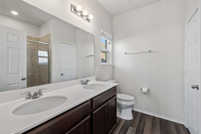 Bathroom featuring laminate / wood-style floors, toilet, walk in shower, and duel vanity | Image 23