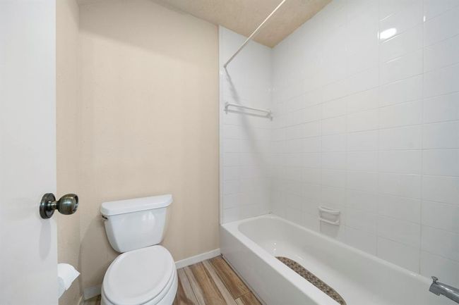 Secondary bath includes a tub-and-shower combination with crisp white tile surround, a built-in soap dish, and a practical towel bar. | Image 30