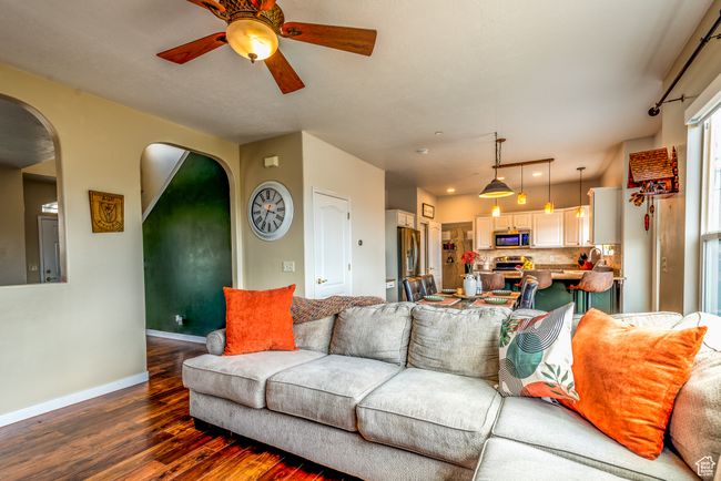 Living room with dark wood finished floors, a ceiling fan, arched walkways, and baseboards | Image 9
