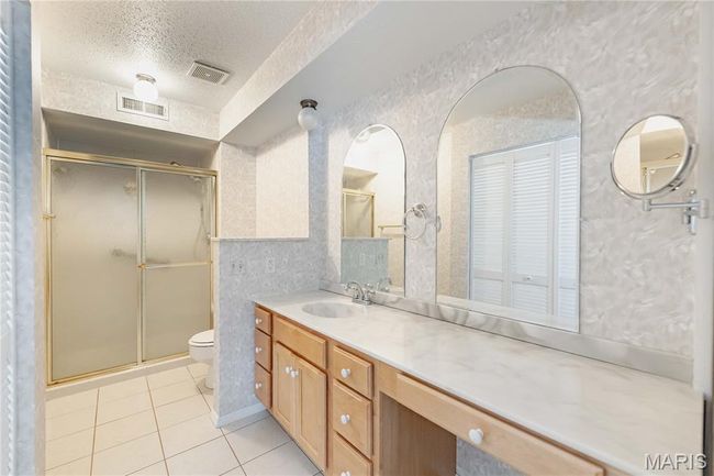 Full bath featuring tile patterned flooring, a textured ceiling, a stall shower, and vanity | Image 36