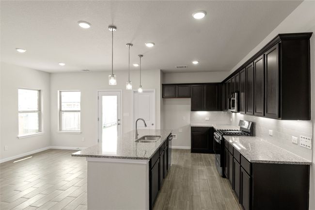 Kitchen with appliances with stainless steel finishes, tasteful backsplash, wood finish floors, light stone counters, and recessed lighting | Image 17