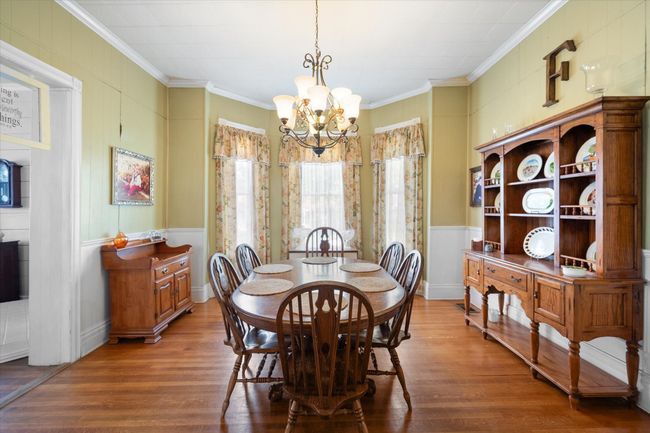 Dining room with a chandelier, crown molding, wood finished floors, and a decorative wall | Image 11
