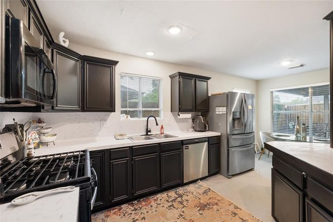 The kitchen is filled with natural light, thanks to a window above the sink and a large side window that offers a clear view of the spacious patio. Picture yourself prepping meals while keeping an eye on the backyard—or stepping out to grill and dine outdoors with ease. | Image 8