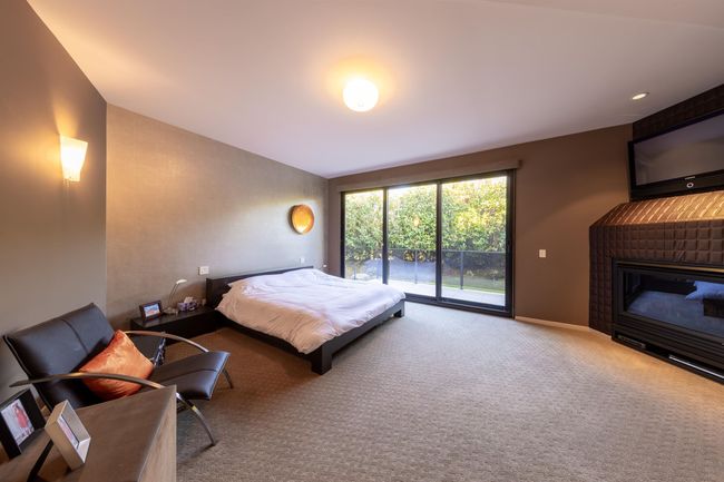 Carpeted bedroom featuring baseboards, access to outside, lofted ceiling, and a brick fireplace | Image 22