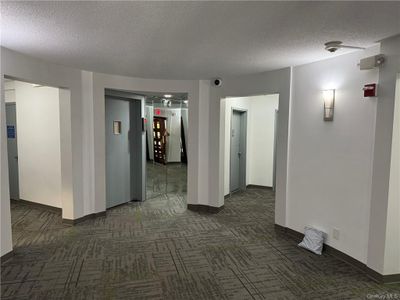 Hall featuring dark carpet and a textured ceiling | Image 2