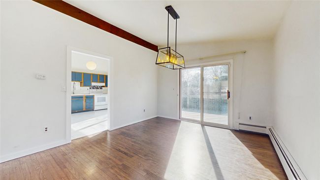 Unfurnished room featuring a chandelier, beam ceiling, baseboard heating, and wood finished floors | Image 8