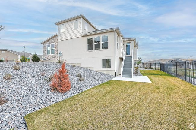 Rear view of property featuring a lawn, fence, stucco siding, a residential view, and stairs | Image 37