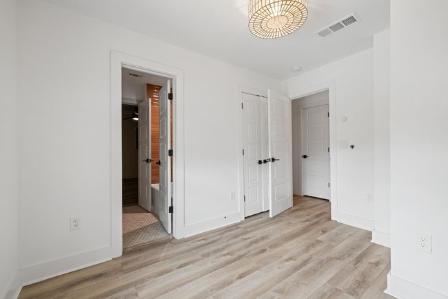 Unfurnished bedroom with ensuite bath, baseboards, light wood finished floors, and visible vents | Image 22