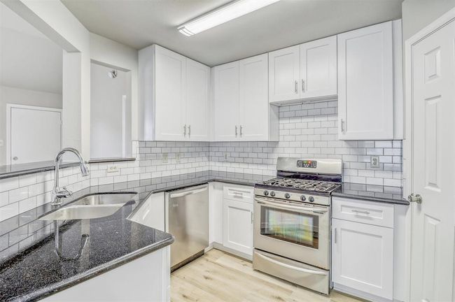 Welcome to the heart of the home—this stunning kitchen features elegant granite countertops, classic shaker-style white cabinets, updated hardware, a timeless white subway tile backsplash. and a gas range. | Image 12