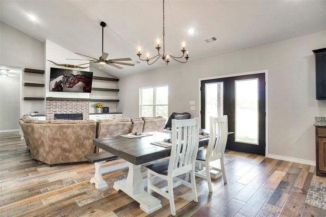 Dining room with vaulted ceiling, hardwood / wood-style flooring, and a brick fireplace | Image 9