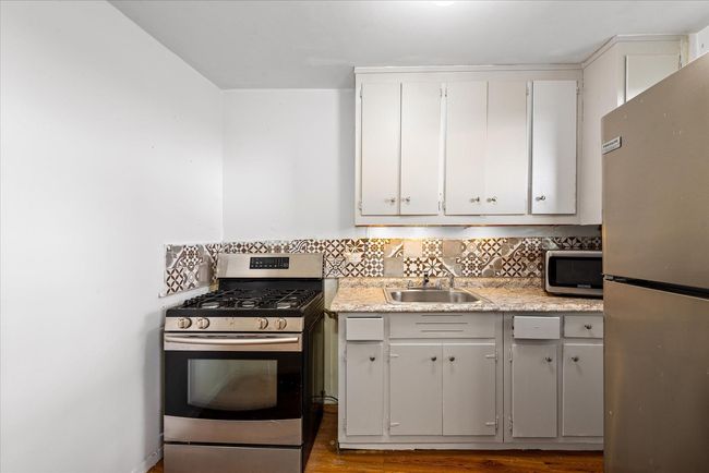 Kitchen with a sink, decorative backsplash, wood finished floors, light countertops, and appliances with stainless steel finishes | Image 7