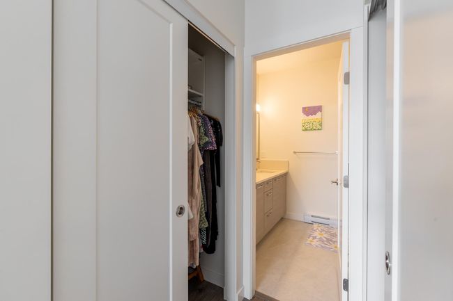 Bathroom with baseboard heating, vanity, a walk in closet, and baseboards | Image 14