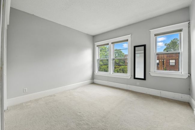 Spacious bedroom with neutral paint, plush carpet, and double windows offering abundant daylight. | Image 19