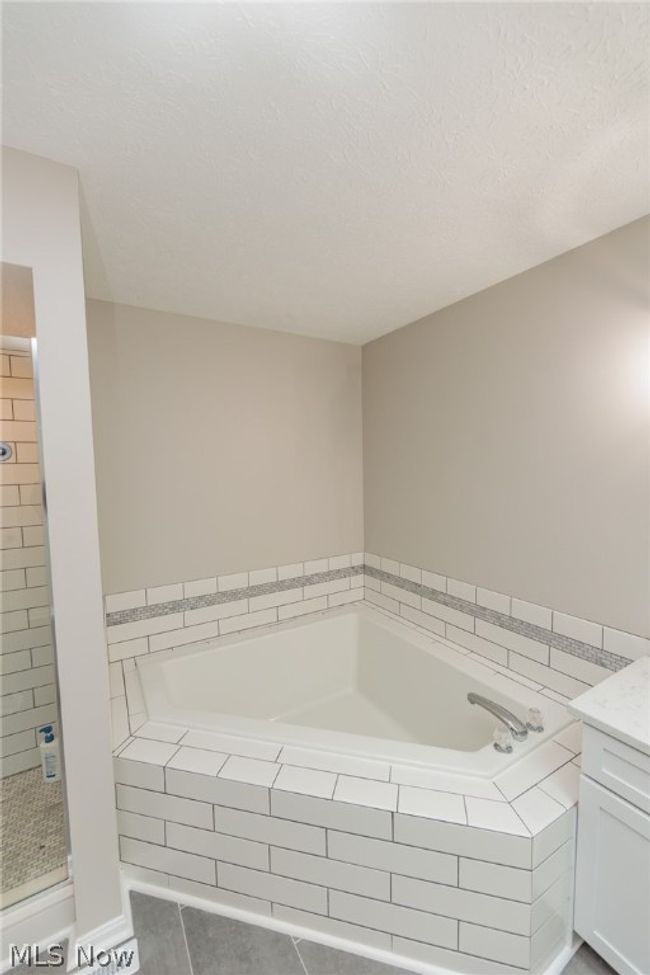 Bathroom featuring separate shower and tub, vanity, a textured ceiling, and tile floors | Image 29