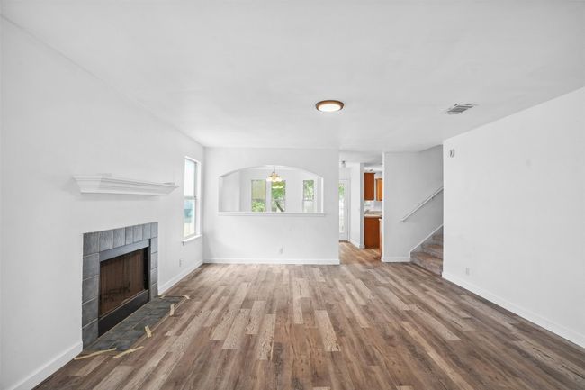 Unfurnished living room with visible vents, stairs, wood finished floors, and a fireplace | Image 6