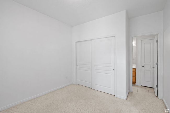Unfurnished bedroom with baseboards, light carpet, and a closet | Image 24