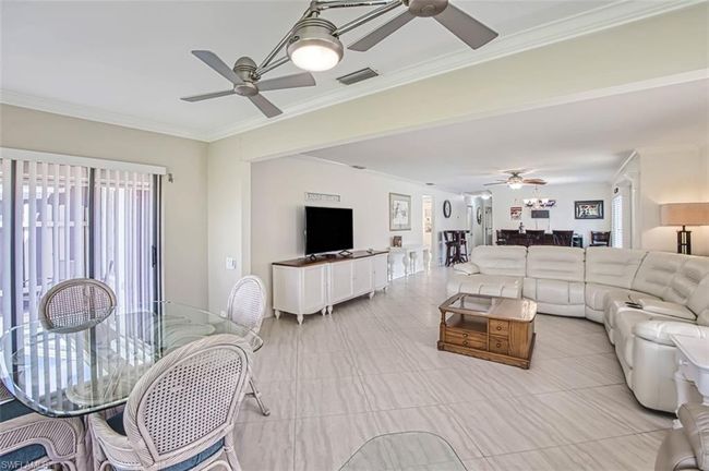 Living room with visible vents, a ceiling fan, and crown molding | Image 13