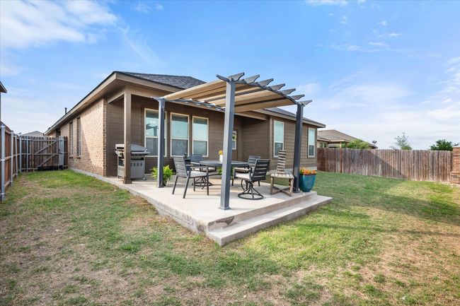 Rear view of house featuring a fenced backyard, a patio, a lawn, and a pergola | Image 33