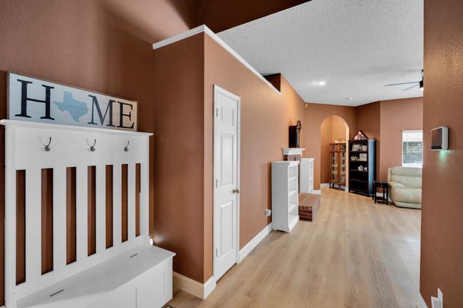 Hallway featuring arched walkways, light wood-type flooring, and a textured ceiling | Image 4