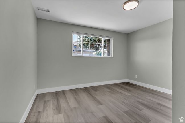 Empty room with wood finished floors, visible vents, and baseboards | Image 18