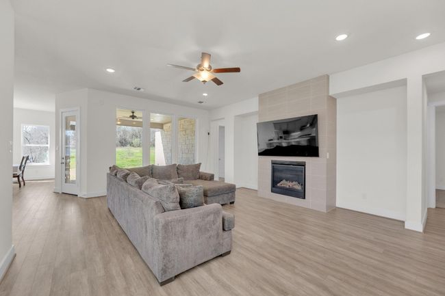 Living room featuring light wood-style flooring, baseboards, a tiled fireplace, and recessed lighting | Image 5