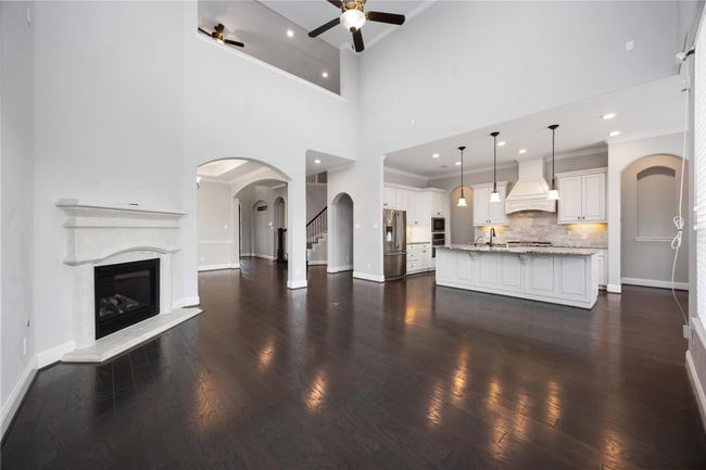 Open-plan kitchen with a large island and elegant pendant lighting. The dark hardwood floors add warmth, while arched doorways provide architectural interest. | Image 14