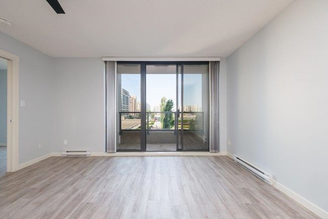 Empty room with expansive windows, wood finished floors, and a baseboard radiator | Image 17