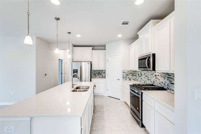 Kitchen featuring appliances with stainless steel finishes, a sink, decorative backsplash, a center island with sink, and recessed lighting | Image 11