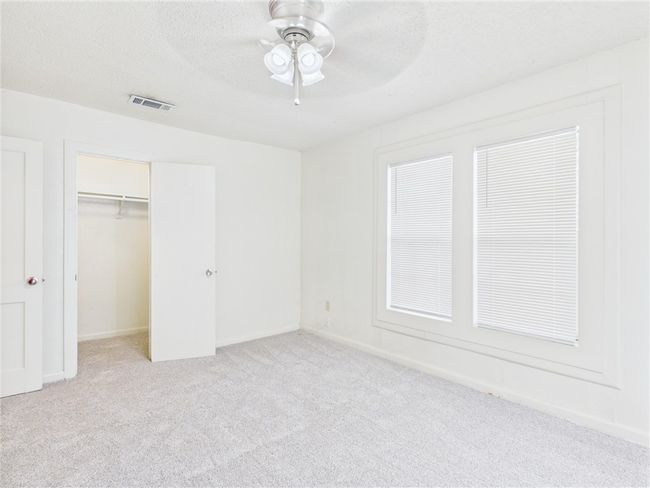 Unfurnished bedroom featuring light carpet, a closet, ceiling fan, and a walk in closet | Image 11