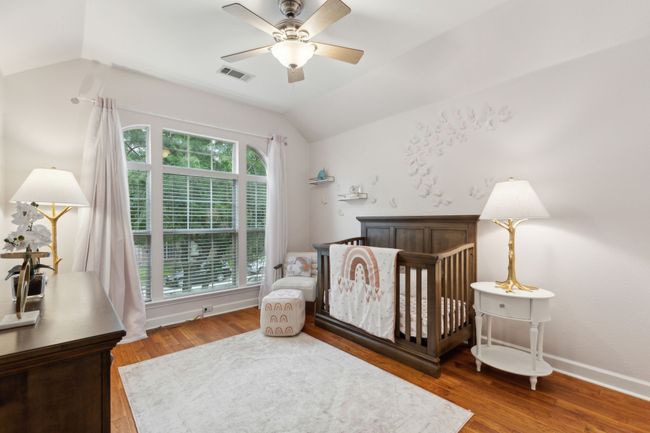 Bedroom featuring vaulted ceiling, wood finished floors, a crib, and a ceiling fan | Image 25