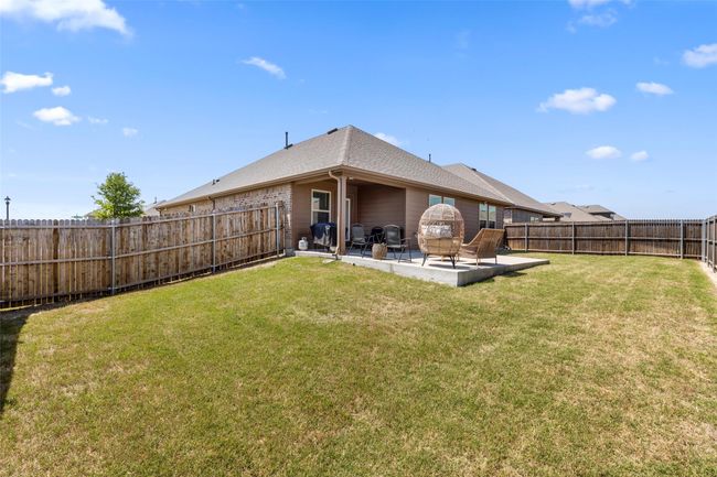 Back of property featuring a patio area, a lawn, a fenced backyard, brick siding, and roof with shingles | Image 4